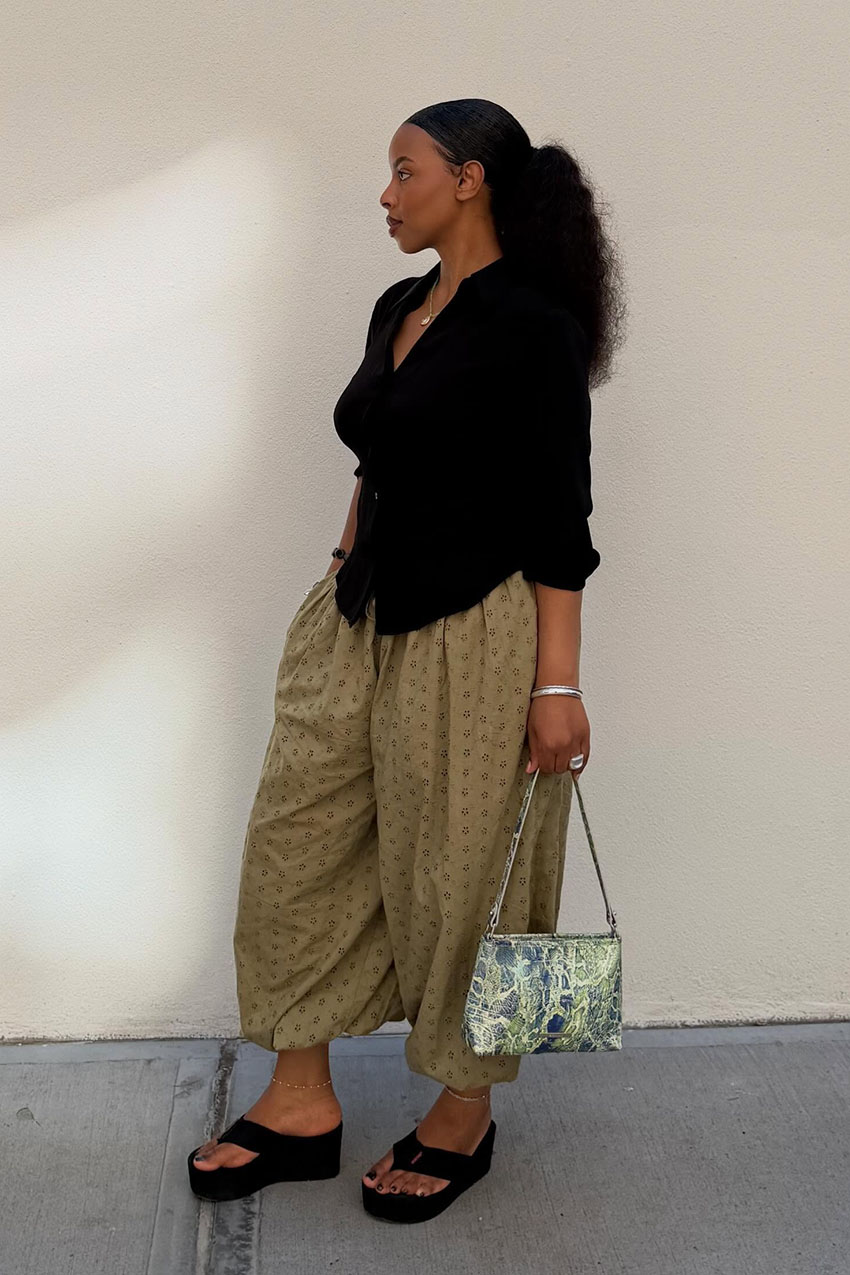 A woman wearing a black long-sleeve top, polka pants, and platform sandals.
