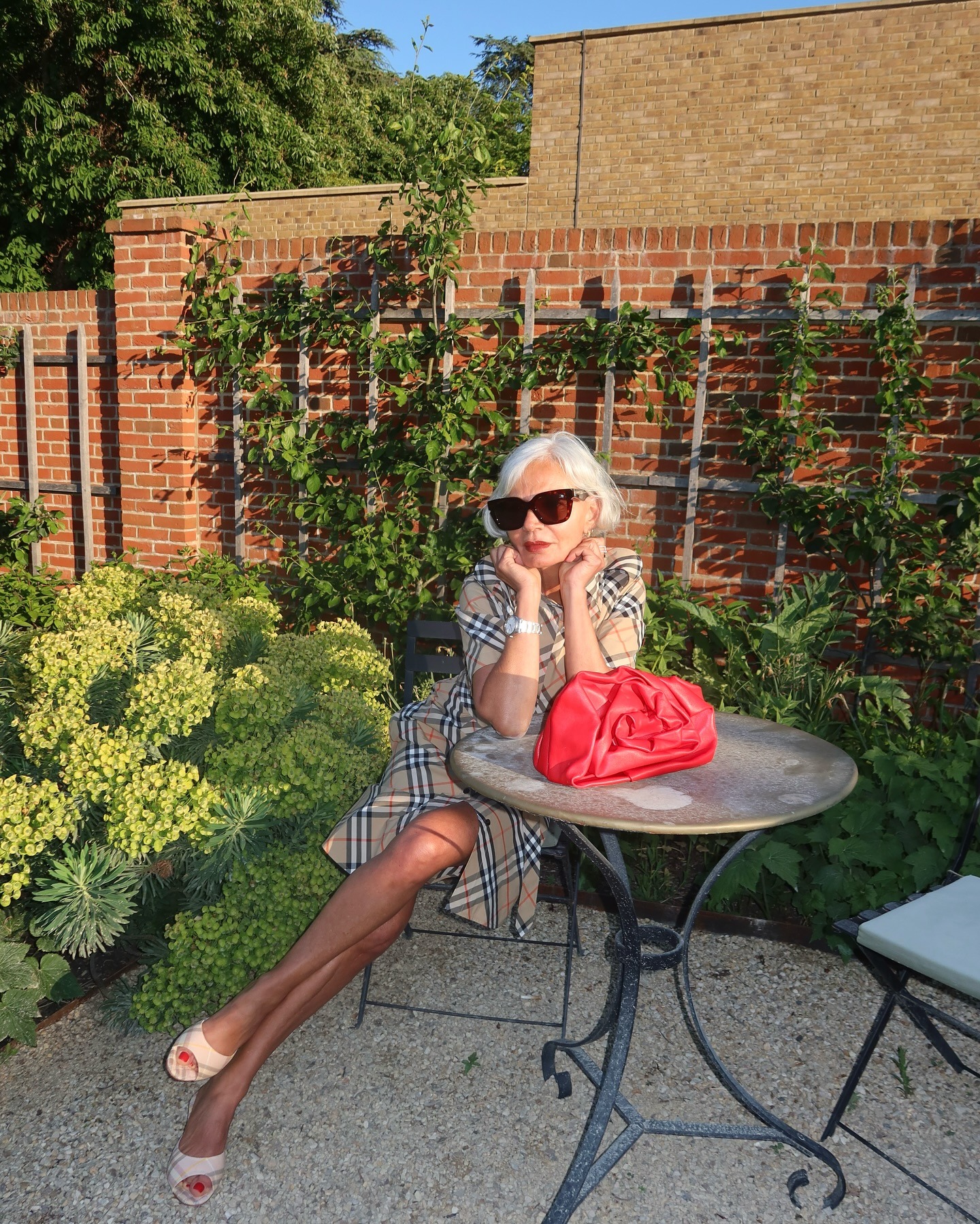 A woman sitting in a garden wearing a burberry dress with sweeping bob hairstyle