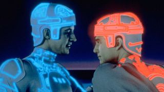 Screenshot from the movie Tron. Two people are facing each other, head-to-head. The person on the left is wearing a white bodysuit and helmet, both with blue light trim. The person on the right is wearing a white bodysuit and helmet, both with orange/red light trim.