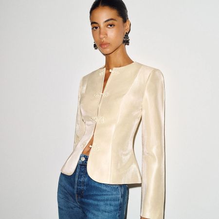 A model in a Reformation ivory satin jacket