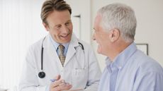 A doctor consults with his patient, an older man.