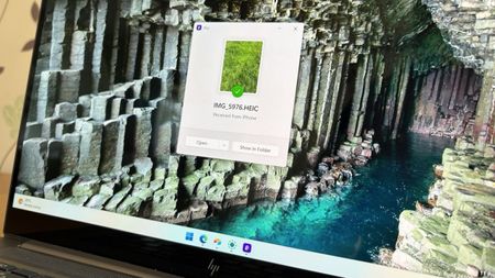A laptop screen displaying a Windows 11 desktop with a Blip file transfer pop-up window confirming a photo was received from an iPhone.