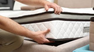 A mattress being fitted to a bed frame