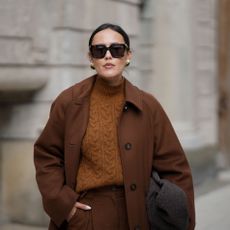 a woman wears a brown cable knit sweater