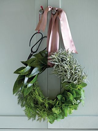 Christmas wreath hanging from a pink ribbon on a cabinet knob with a pair of scissors