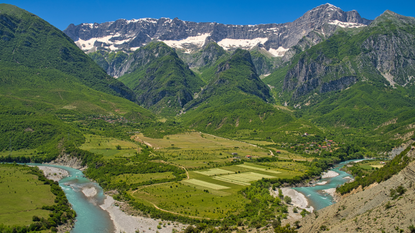 A view across a bend in the Vjosa river, surrounded by mountains 