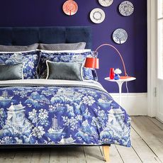 violet coloured bedroom with dish on wall and bed linen