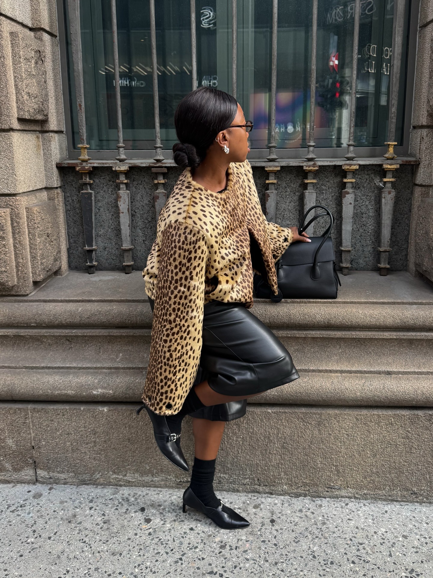 A woman wearing a leopard print jacket with a shiny brunette bun hairstyle