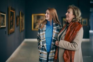 A mother and daughter looking at classic paintings in an art gallery together.