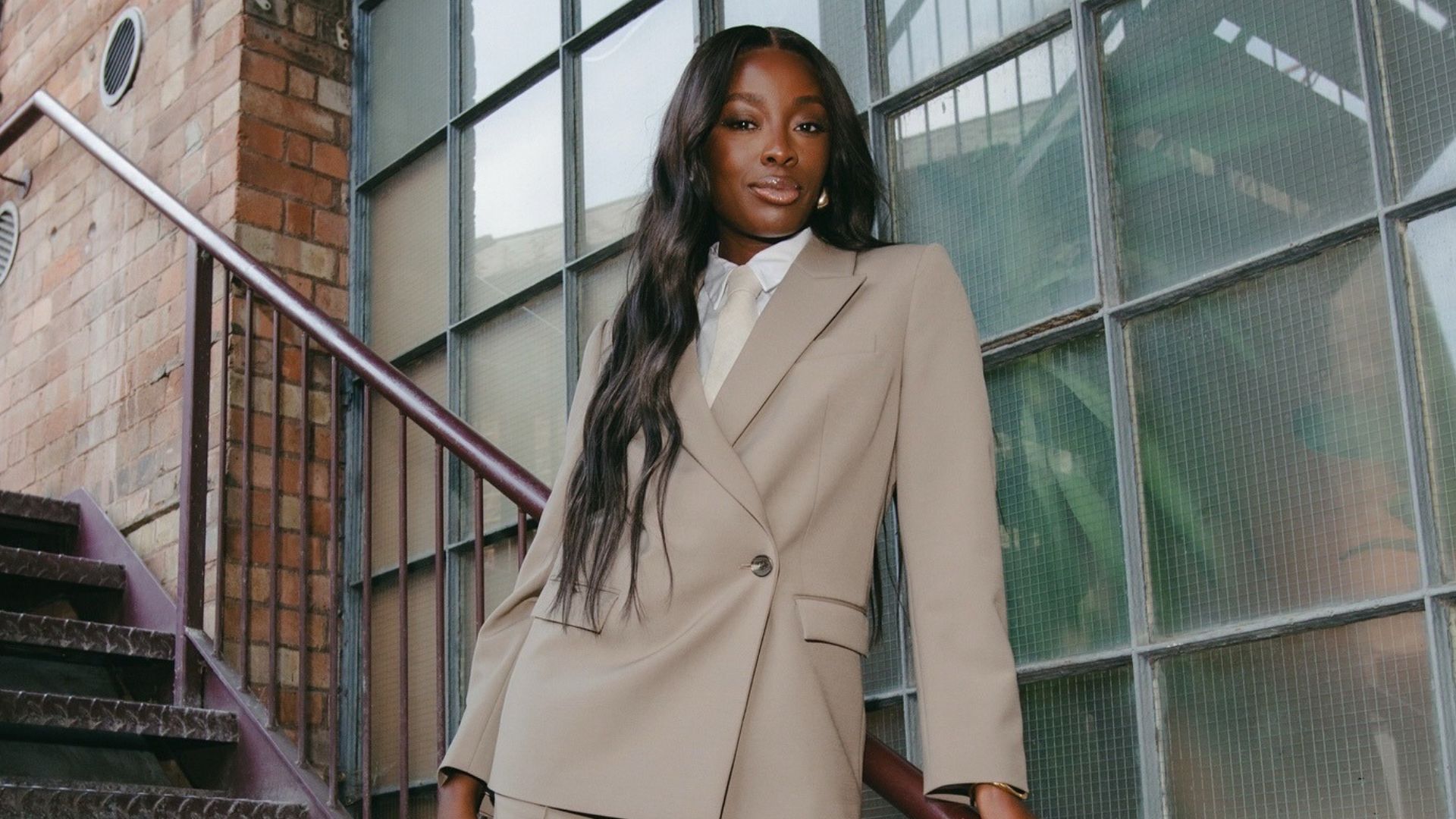 Model wears Marks and Spencer black slip dress with red bag and white kitten heel shoes.
