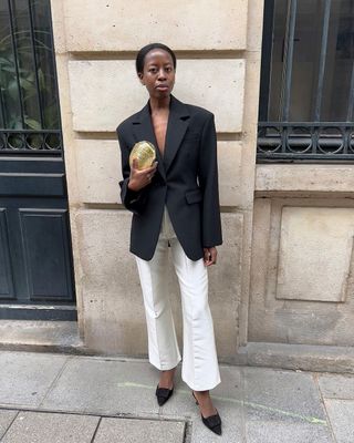 fashion influencer Sylvie Mus wearing a black blazer with white trousers and Manolo Blahnik Maysale Mules