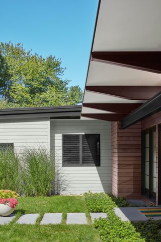 The outside of a house with a green lawn and walls painted in a gray shade