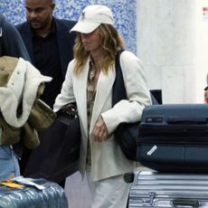 Philippine Leroy-Beaulieu walks through the airport wearing white trainers with white jeans and a white blazer.