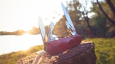 A multipurpose tool sits open on a rock in the sun.