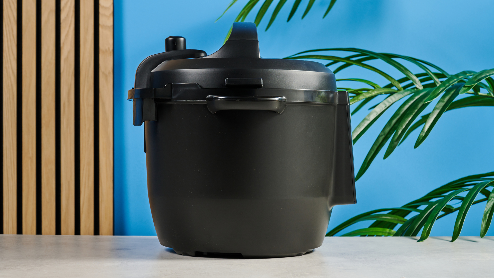 a black pressure cooker photographed against a blue background, showing its cooking presets, steam release valve, and Instant Pot branding