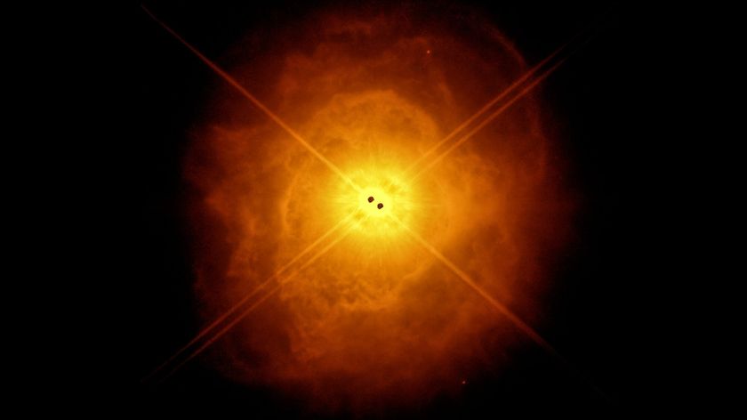 two black hots in the center surrounded by a dusty orange glowing egg-shaped cloud of gas and dust.