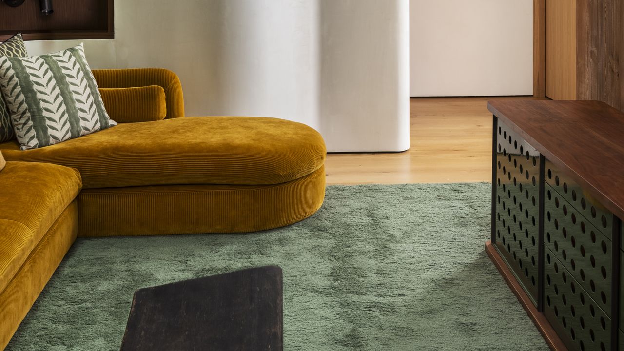 living room with large green rug and yellow sofa