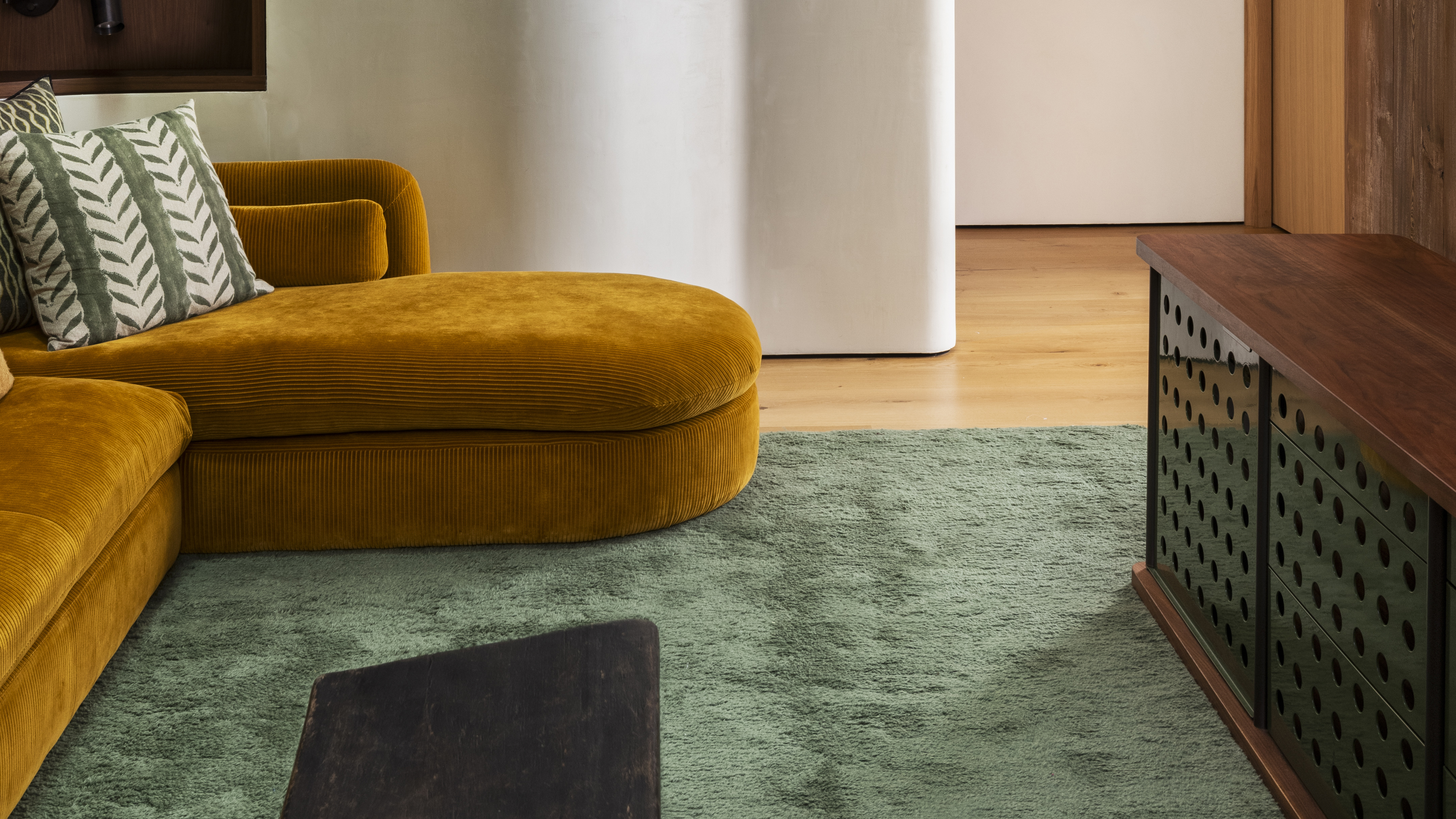 living room with large green rug and yellow sofa