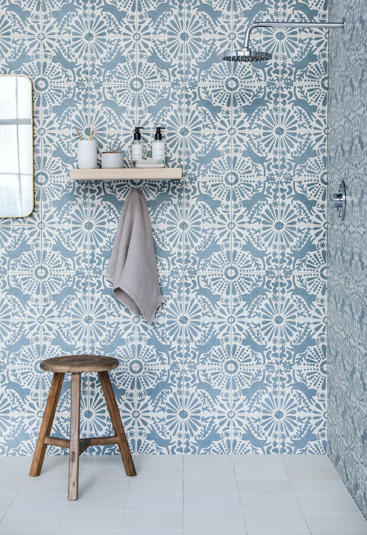 Blue patterned shower room tile, blue floor tile, mirror, shelf and bench