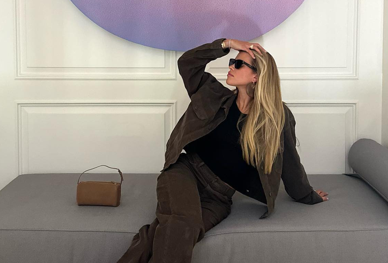 Sofia Richie Grainge wearing The Row brown '90s bag while sitting on grey couch.
