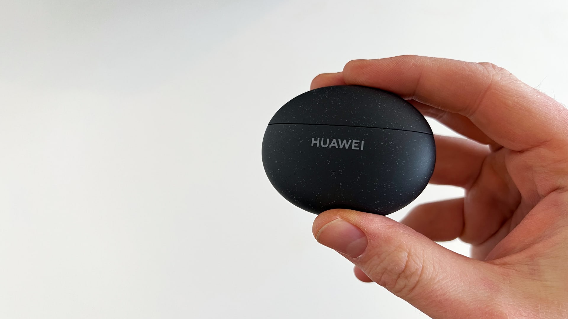 Ørepropper av typen Huawei Freebuds 5i i en hånd mot en hvit bakgrunn.