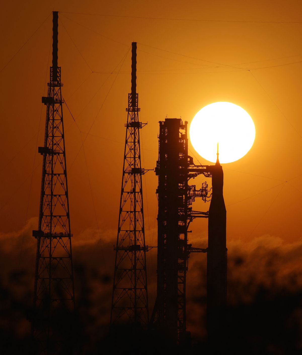 A rocket is stands in silhouette in front of a sunset.