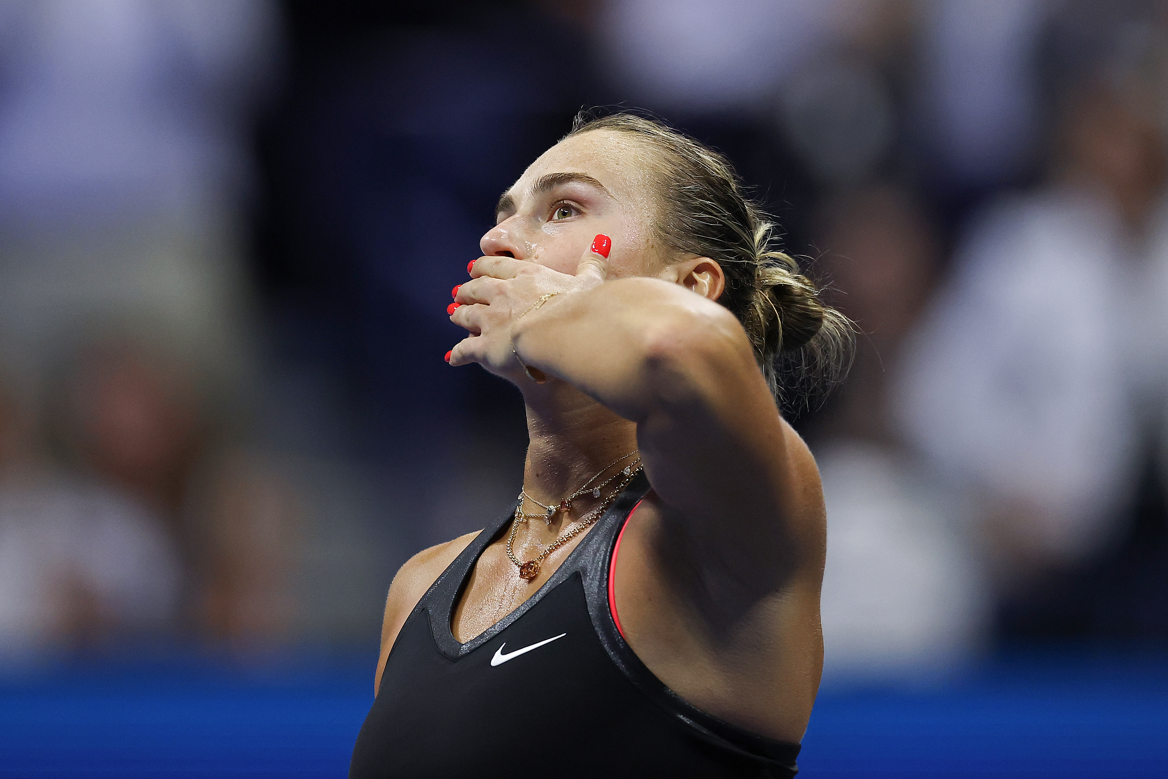 Aryna Sabalenka with red nails and wearing a black dress blowing a kiss to the crowd