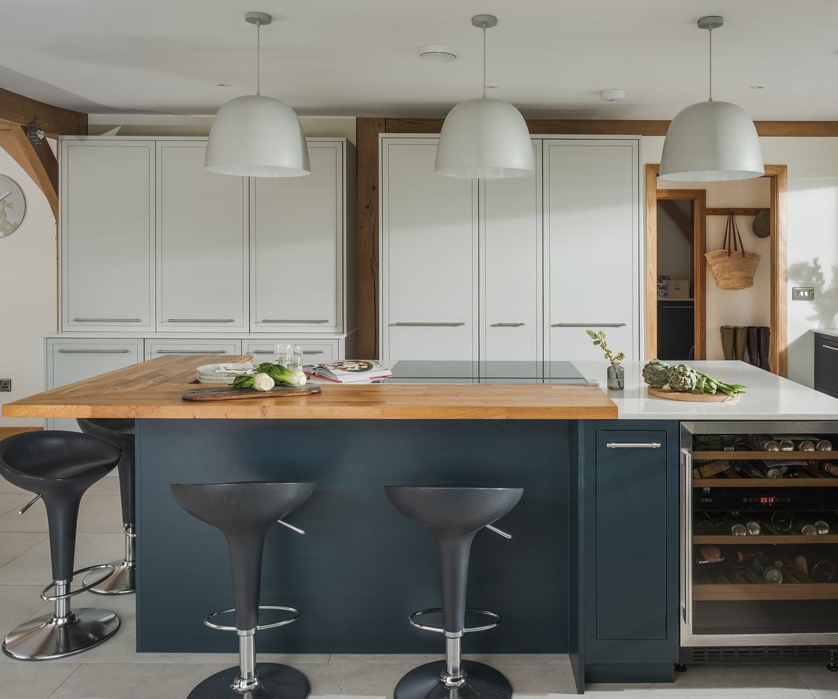 A kitchen island with bar stools and light and dark contrasting cabinets
