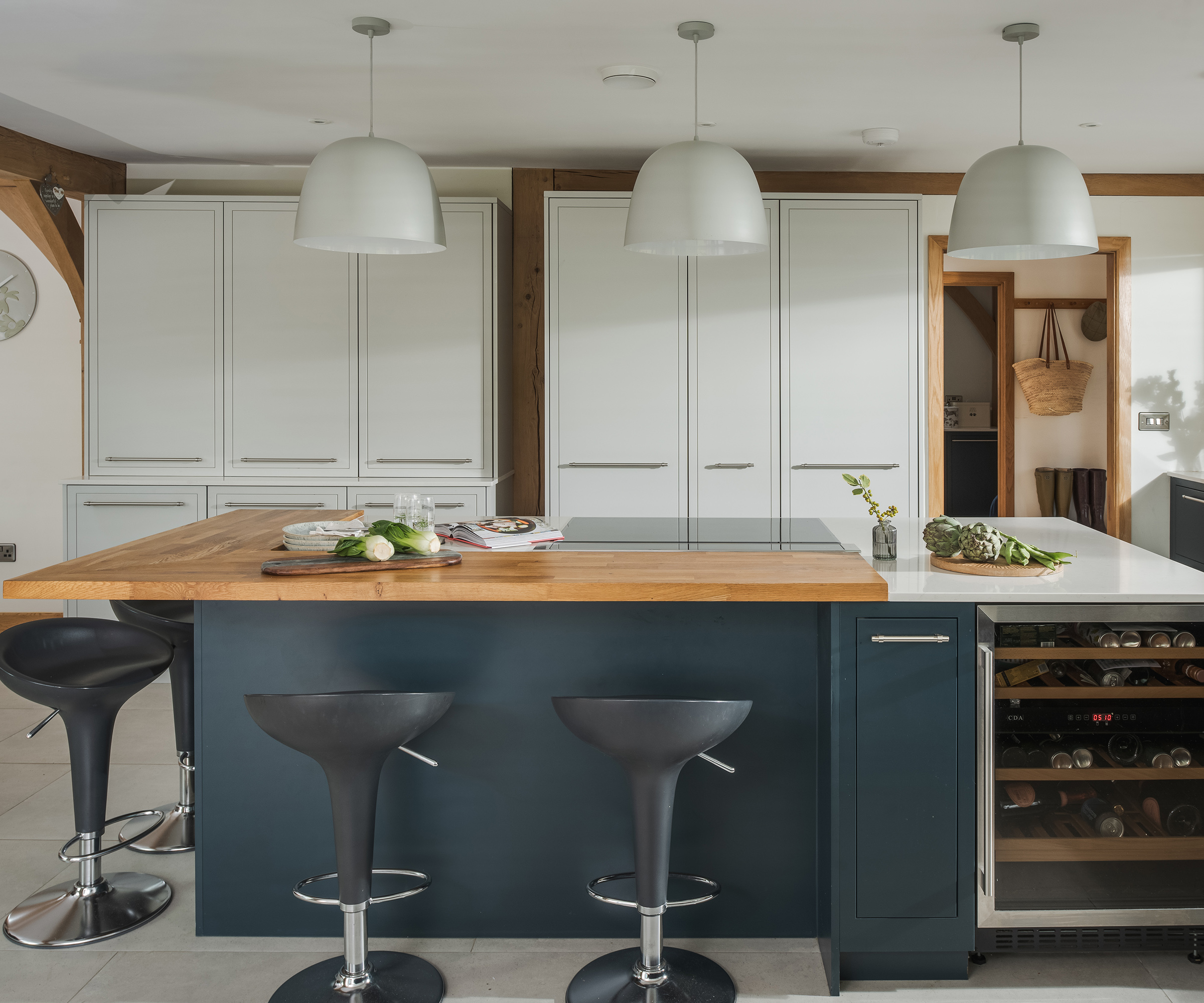 A kitchen island with bar stools and light and dark contrasting cabinets