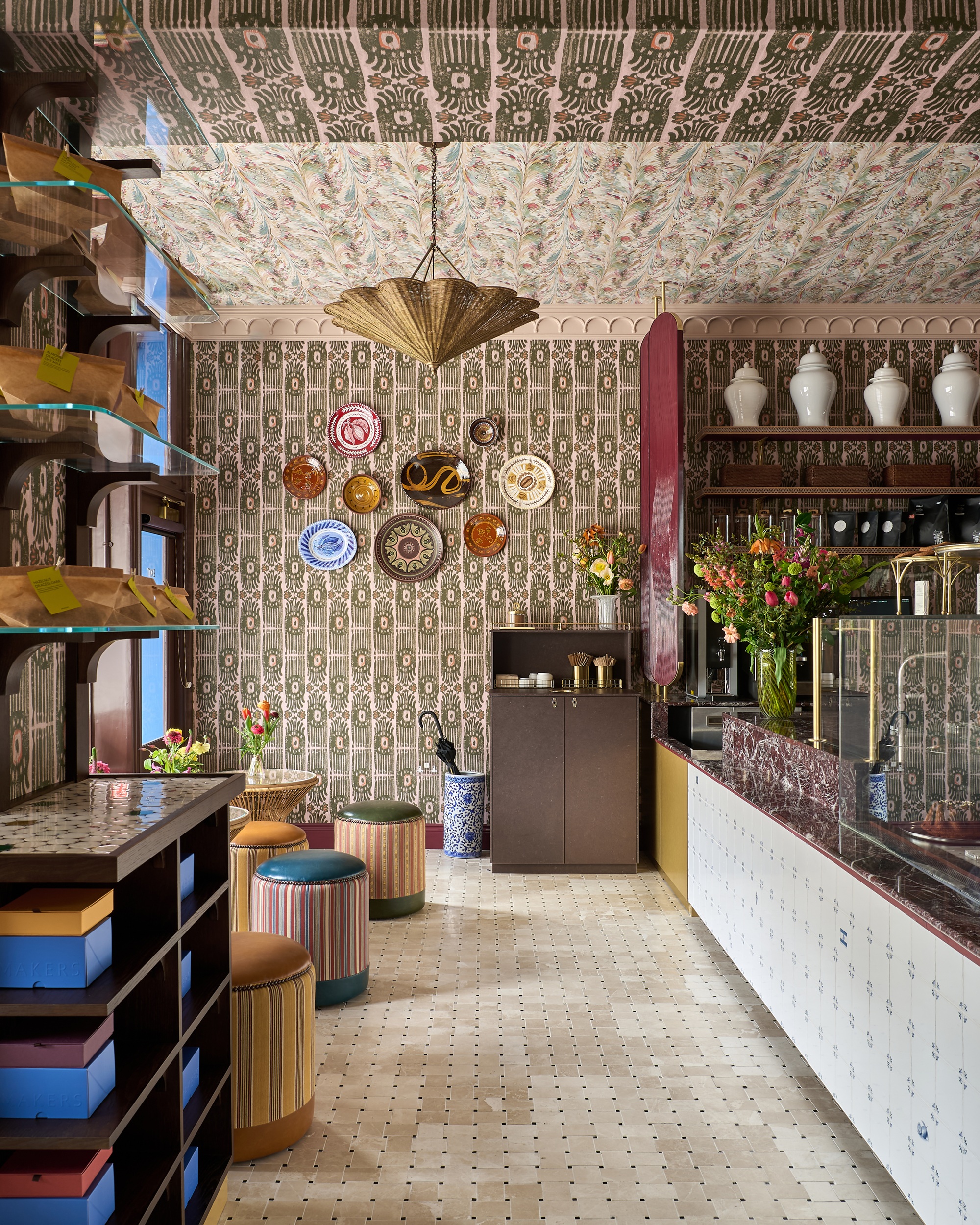 the interiors of a chocolate shop in London with wallpaper on the walls and ceiling, a rattan shade and plates on the wall