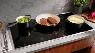 GE appliance induction cooktop with cast iron pans on top