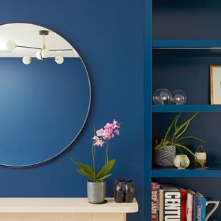 living room with teal blue wall and round mirror on it