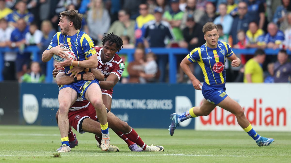 Warrington&#039;s Adam Holroyd is tackled by Wigan&#039;s Junior Nsemba during the sides&#039; Super League encounter in June 2024.