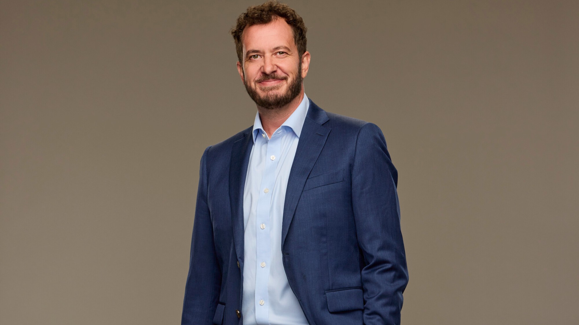 Rick Devens cast photo of Big Brother Season 28. He's wearing a blue sport jacket and smiling. 