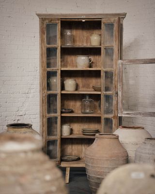 A cupboard filled with decorative pots and antique confit jars