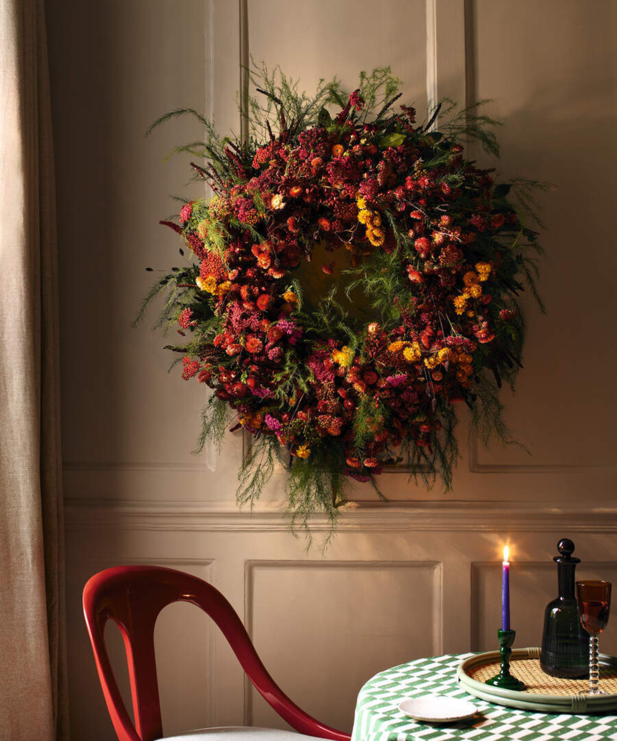 a large, colorful wreath hanging on the wall in front of a table and a chair