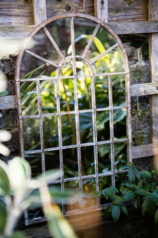 rustic garden mirror leaning against a fence