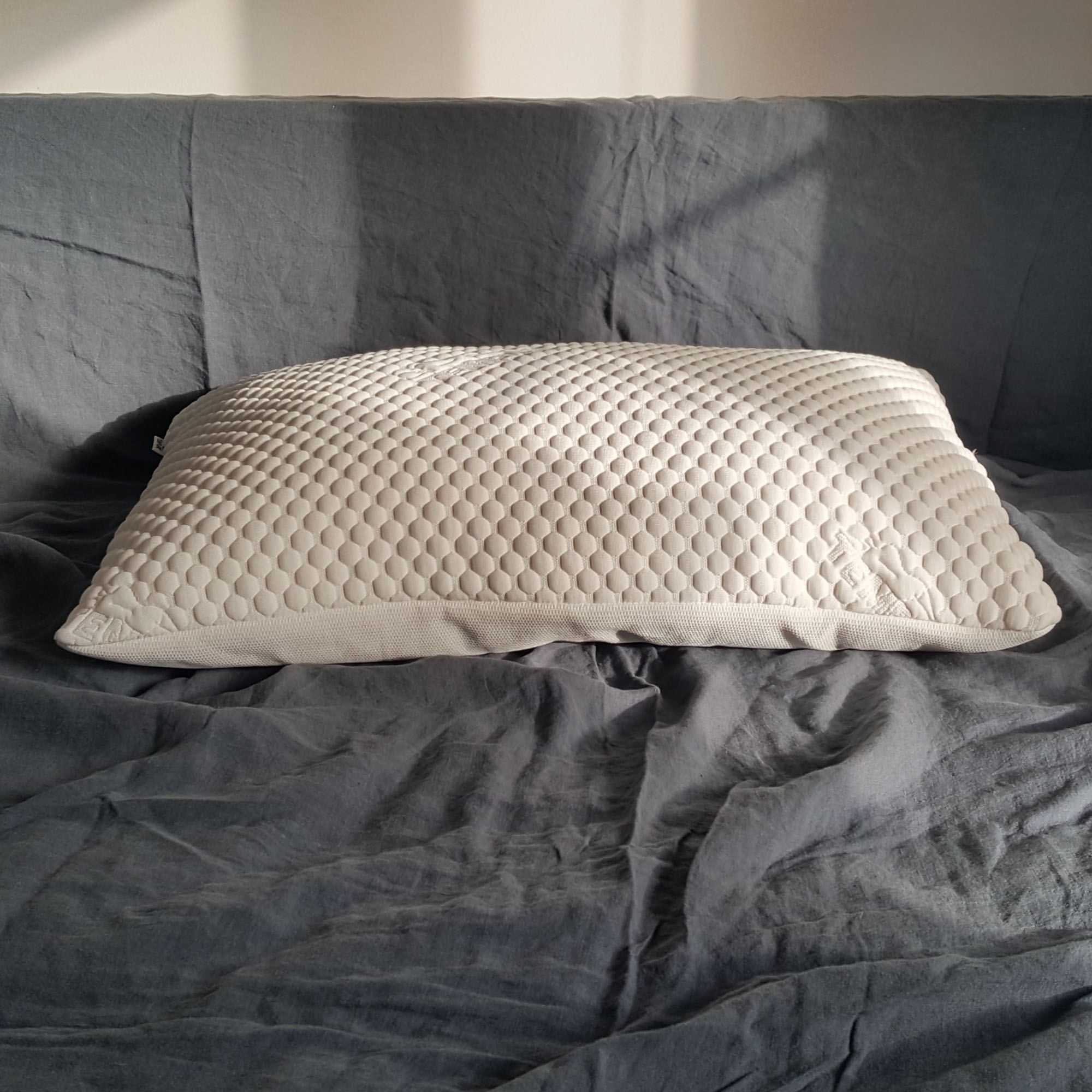 The Tempur Comfort Cloud pillow being tested on a bed with grey bedlinen