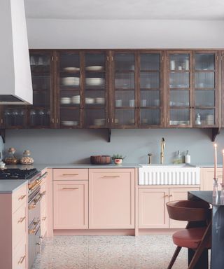 A kitchen with minimalistic backsplash and pink cabinetry