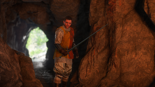 Kingdom Come Deliverance RPG screenshot showing hero Henry wielding his sword in a cave