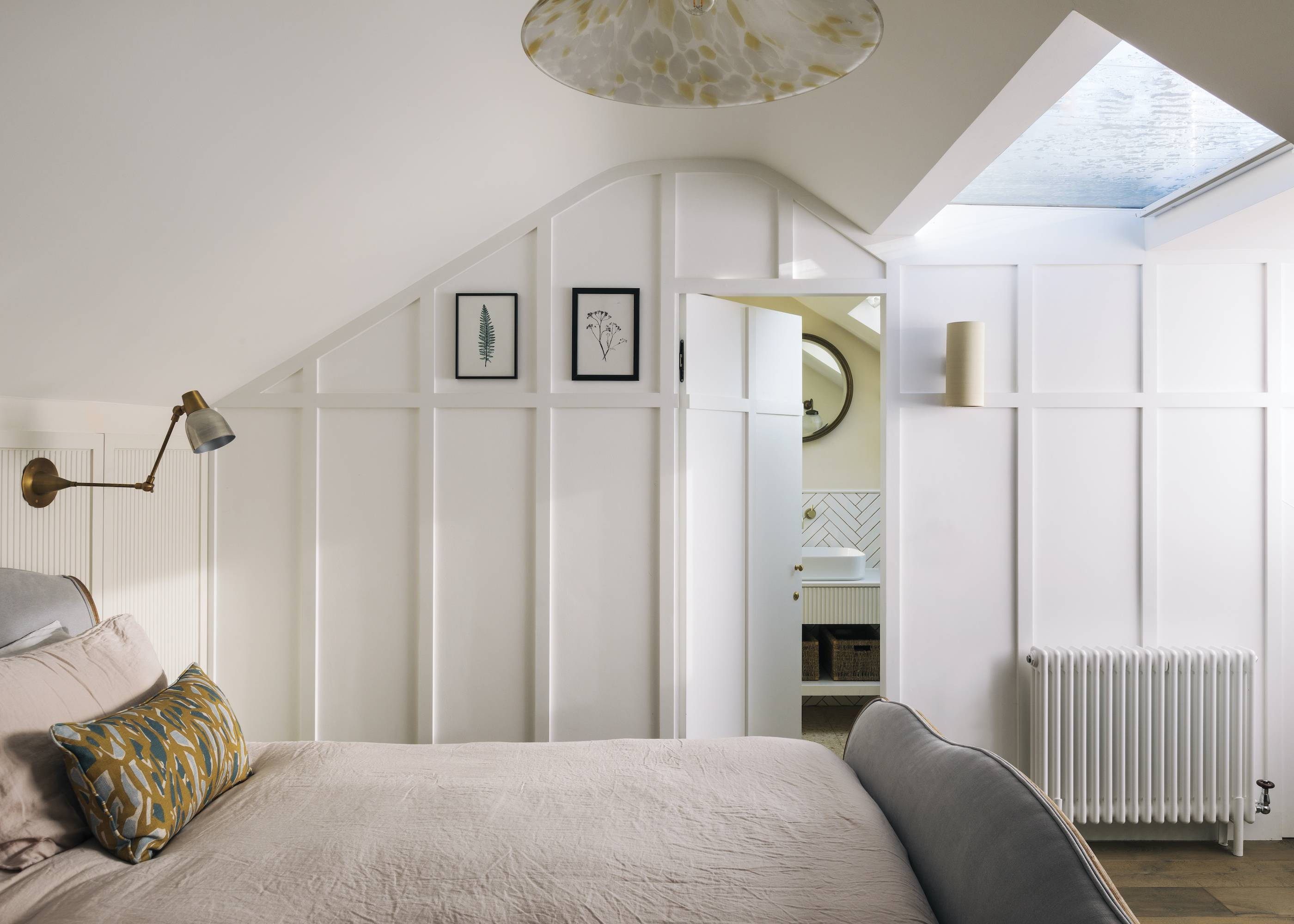 loft conversion with bed and panelled wall leading to ensuite