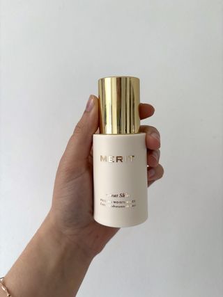 Mica Ricketts holding bottle of Merit Great Skin Priming Moisturizer