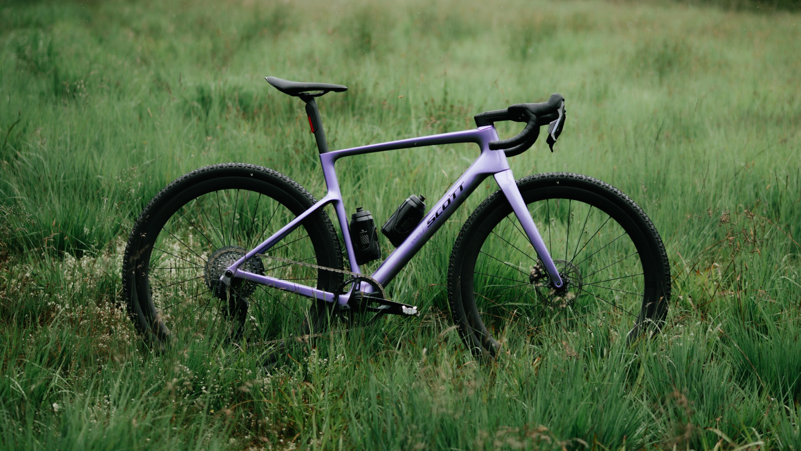 A purple Scott Addict gravel bike in a grassy field 