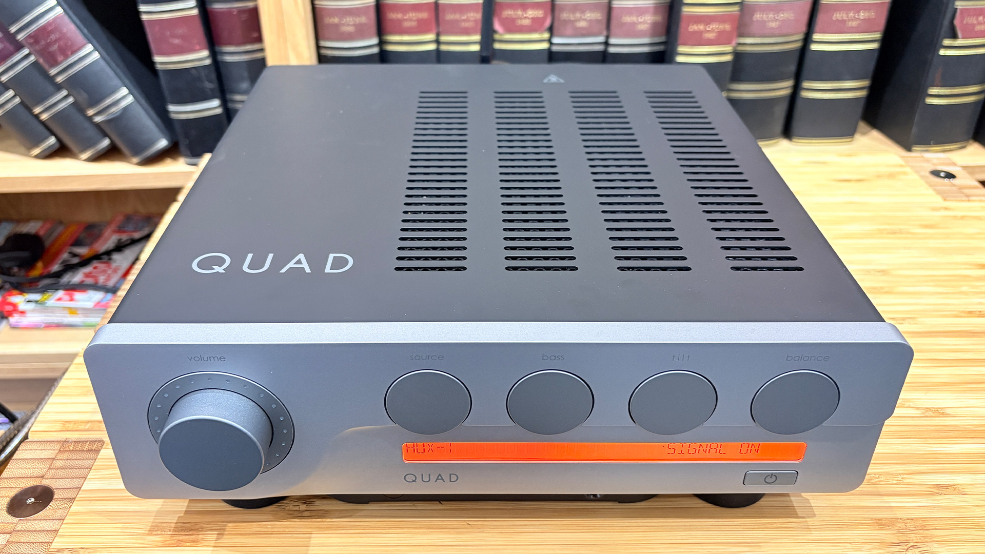 Quad 3 integrated amplifier on wooden hi-fi rack in front of bookcase slight top-down view