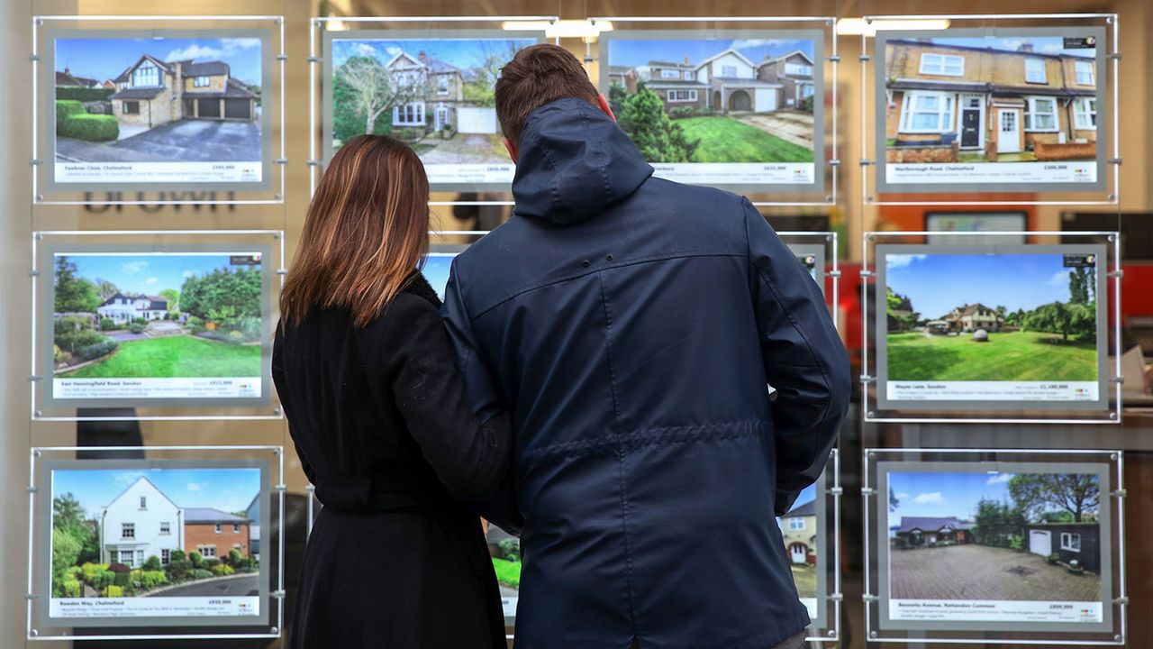 A couple looking at houses in an estate agent&amp;#039;s window