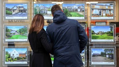 A couple looking at houses in an estate agent's window