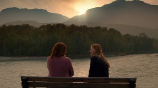 Charmaine and Mel sitting on a bench by the lake in Virgin River