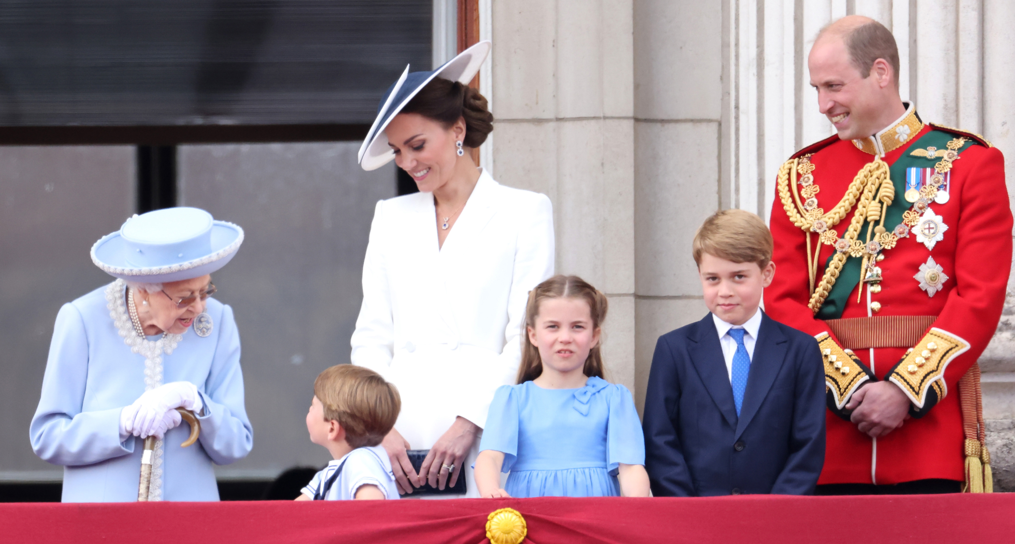 Queen Elizabeth talking to Prince Louis on the palace balcony as Princess Kate, Prince William, Princess Charlotte and Prince George look on