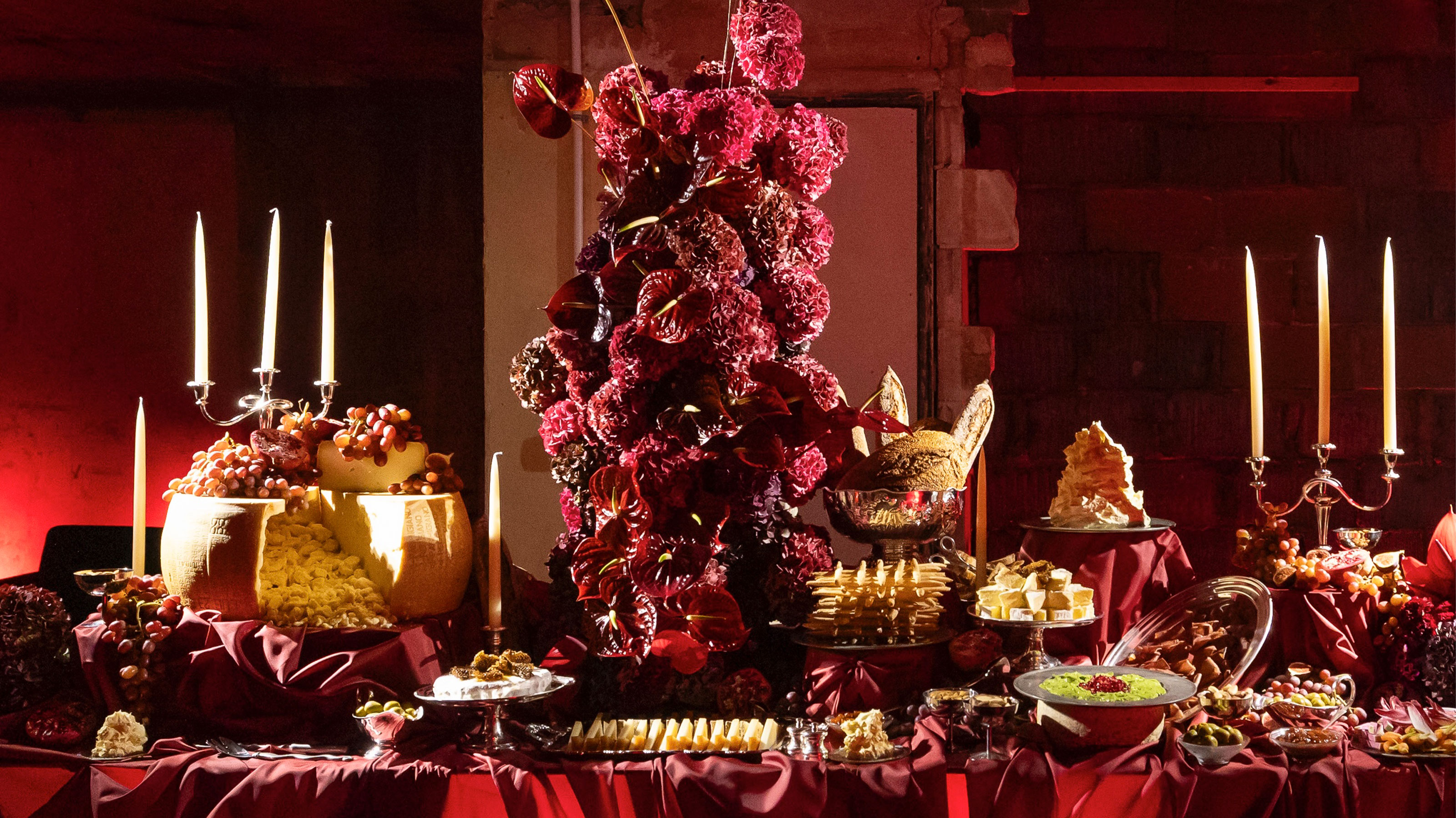 a tablescape all in red with dramatic florals, candles, and food