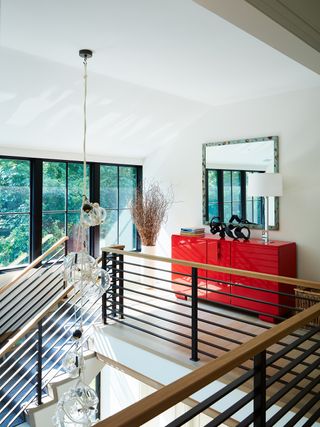 bright red cabinet covered in gloss paint on a landing by a modern staircase
